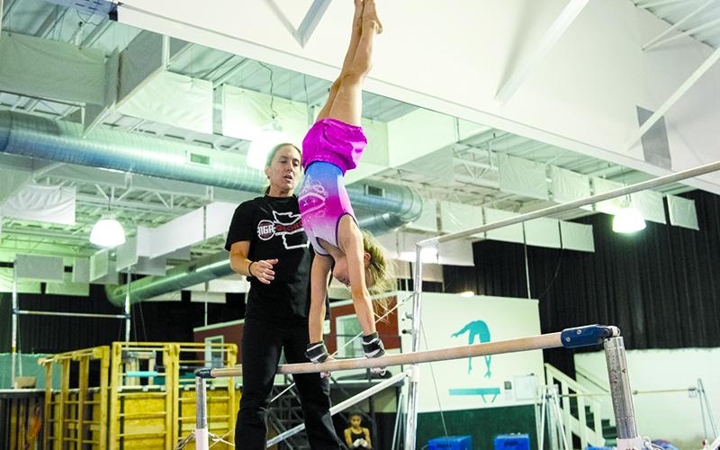 Remmi Raley gets spotted during a bar routine by Coach Jessica Rockwell at Thursday’s practice. ZACH TAYLOR/Special